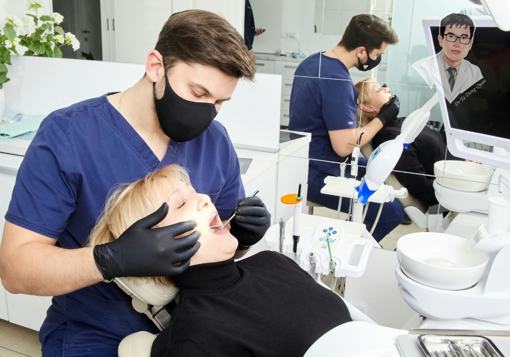 Điều trị tụt nướu – Đừng chần chừ đến gặp nha sĩ ngay hôm nay! Một bệnh nhân đang được nha sĩ kiểm tra và tư vấn về tình trạng tụt nướu. Điều này nhấn mạnh tầm quan trọng của việc thăm khám nha khoa định kỳ.